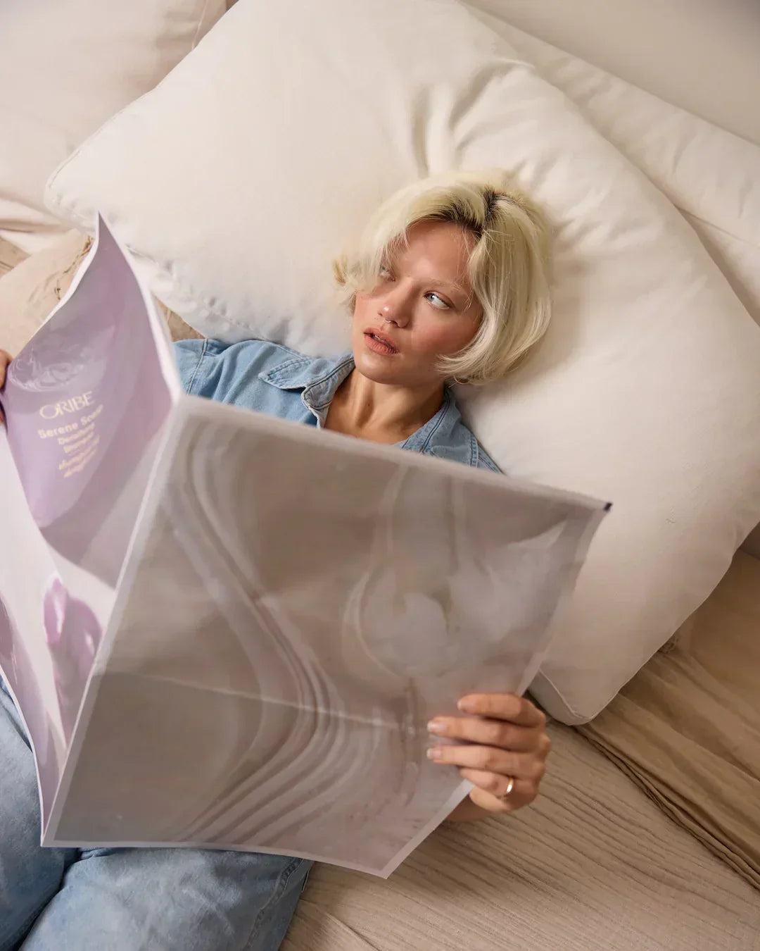 woman holding newspaper with oribe imagery on it
